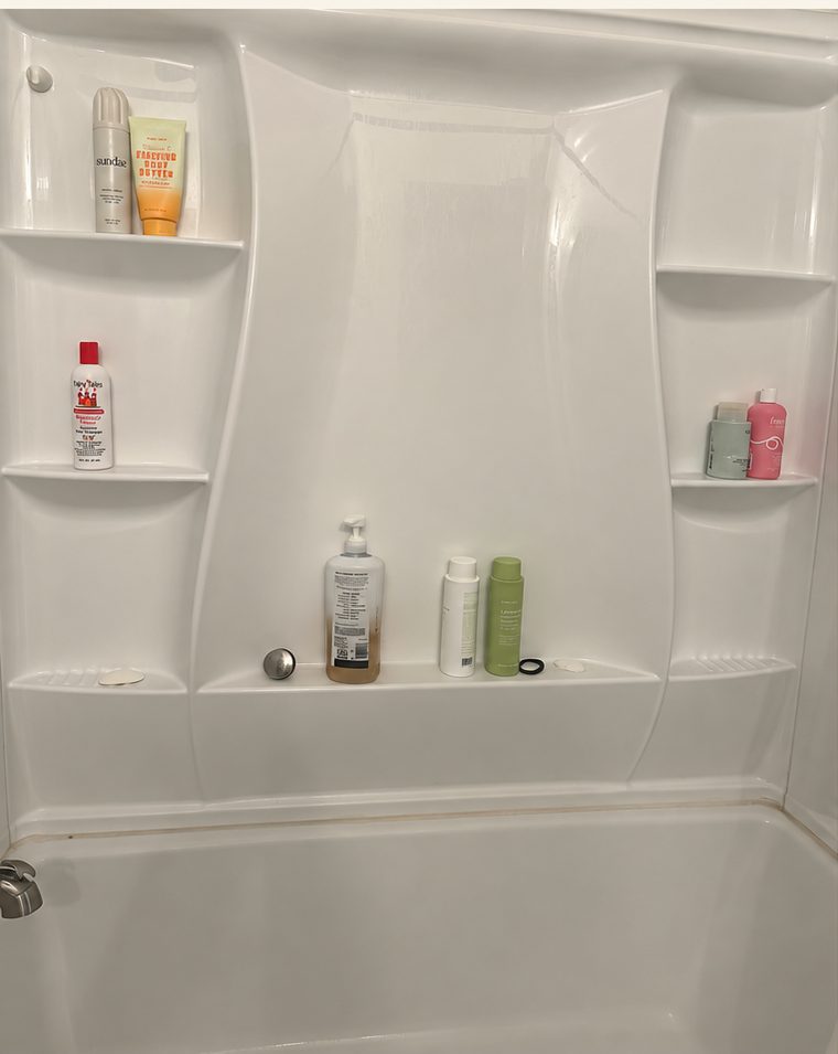 Shower before cleaning with soap scum and scattered bottles